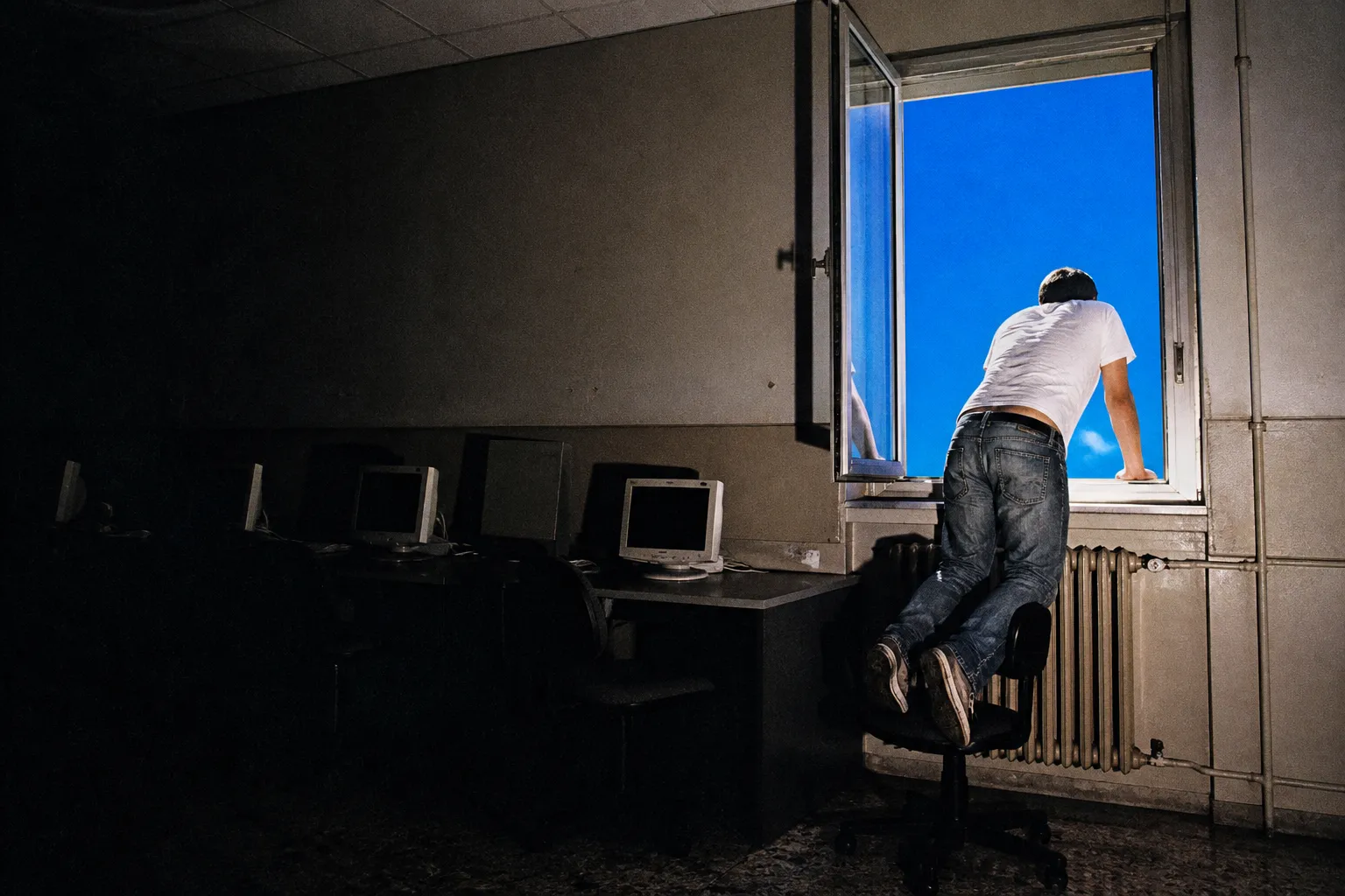 A person climbing toward a blue sky through an office window